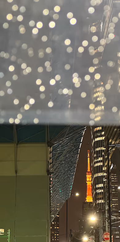 Tokyo Tower at night, seen through a rain-speckled window